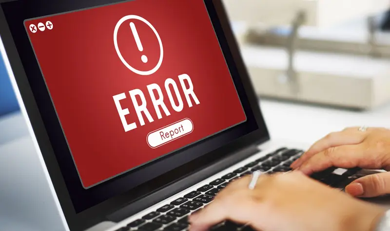 A person is typing on the laptop with error message.